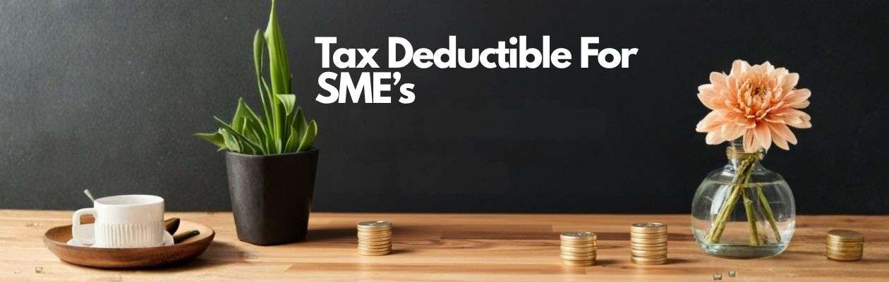 A wooden table with a cup, two plants, and stacks of coins. Text reads Tax Deductible For SMEs. A wooden table with a cup, two plants, and stacks of coins. Text reads Tax Deductible For SMEs.