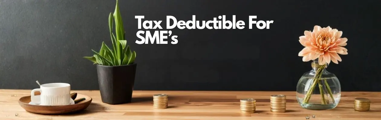 A wooden table with a cup, two plants, and stacks of coins. Text reads Tax Deductible For SMEs. A wooden table with a cup, two plants, and stacks of coins. Text reads Tax Deductible For SMEs.